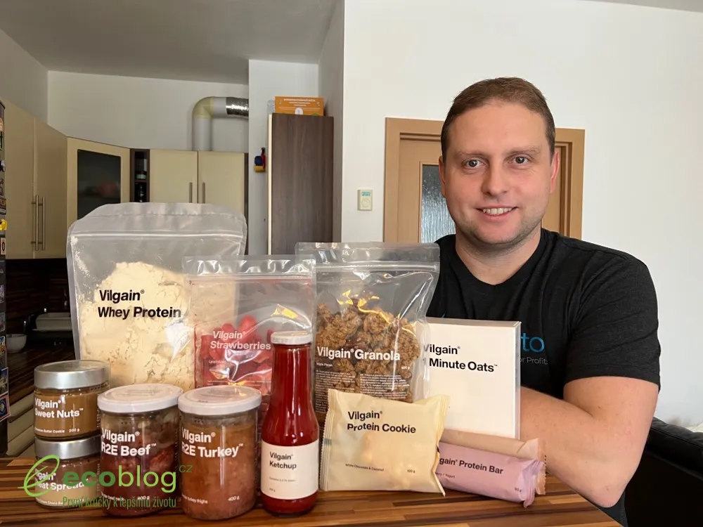 Autor recenze u stolu s jedenácti produkty Vilgain, mezi nimi whey protein, granola, kečup, oříškové krémy a zavařené maso