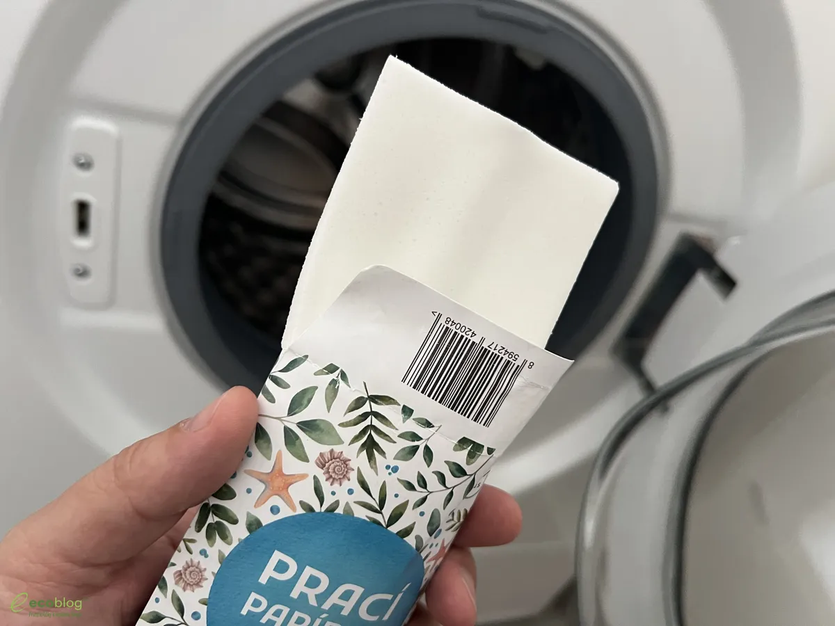 Ruka vkládá prací papírek EcoHaus do bubnu pračky