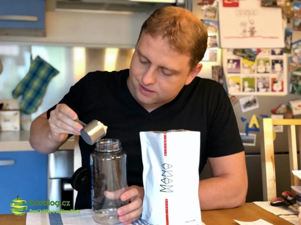 Připravený nápoj Mana v shakeru vedle odměrky a otevřeného sáčku prášku