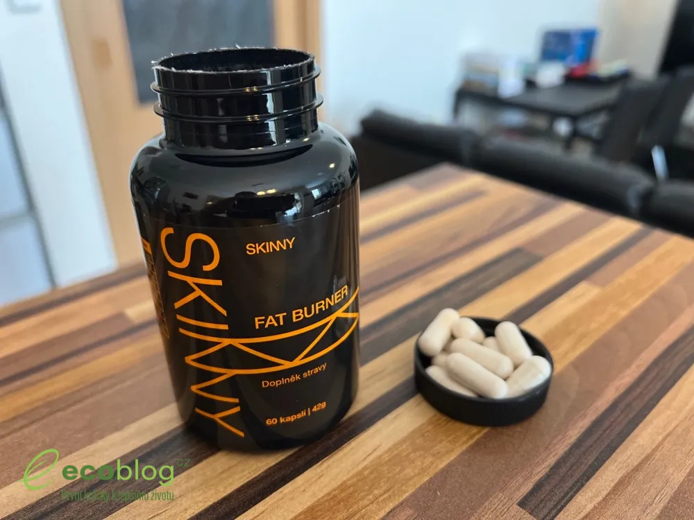 Otevřená černá dóza Skinny Fat Burner s bílými kapslemi ve víčku na dřevěném stole