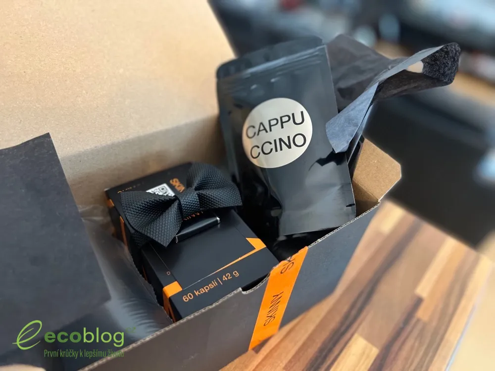 Krabička Skinny Fat Burner vedle stříbrného sáčku Cappuccino na dřevěném stole
