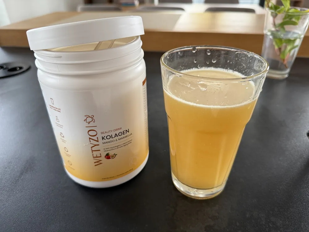 Sklenice s hotovým kolagenovým nápojem WETYZO mango a marakuja vedle dózy